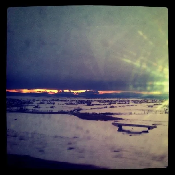Orange sunset over a snowy landscape with frozen water and a bridge in Suceava
