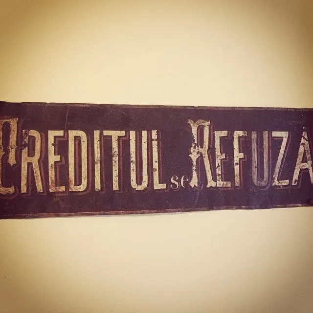 A vintage wooden sign on the wall reading CREDIT DENIED in weathered lettering.