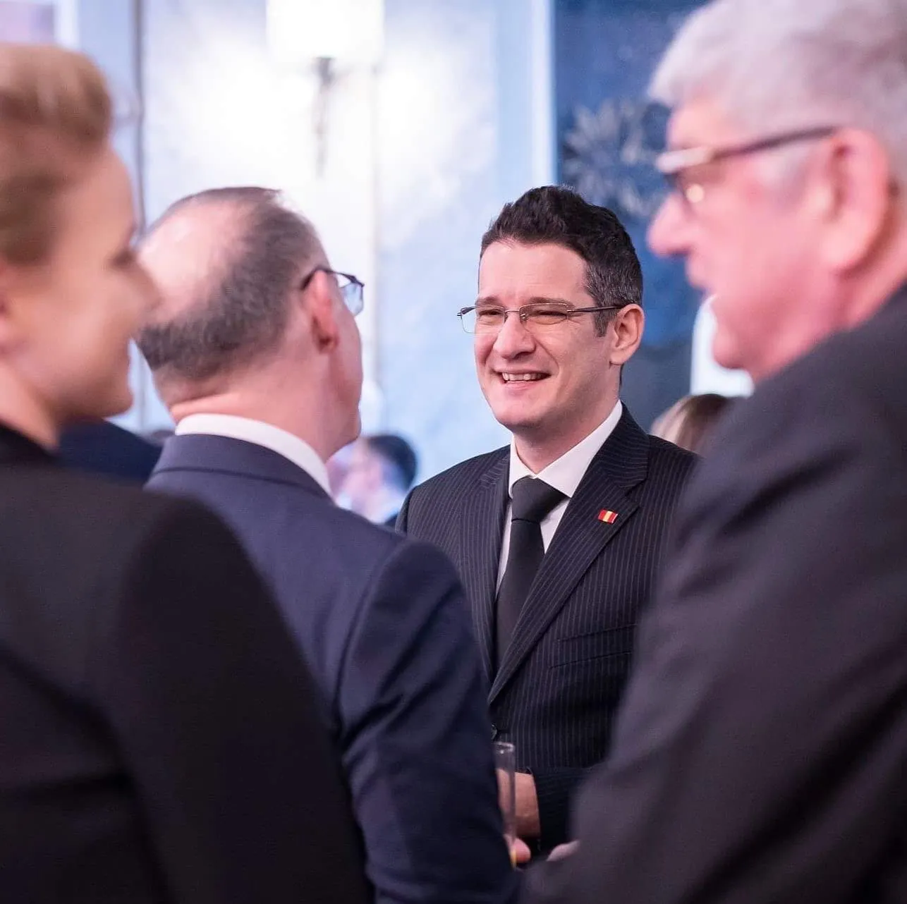 Sebastian Cochinescu smiles while speaking with guests at a formal reception.