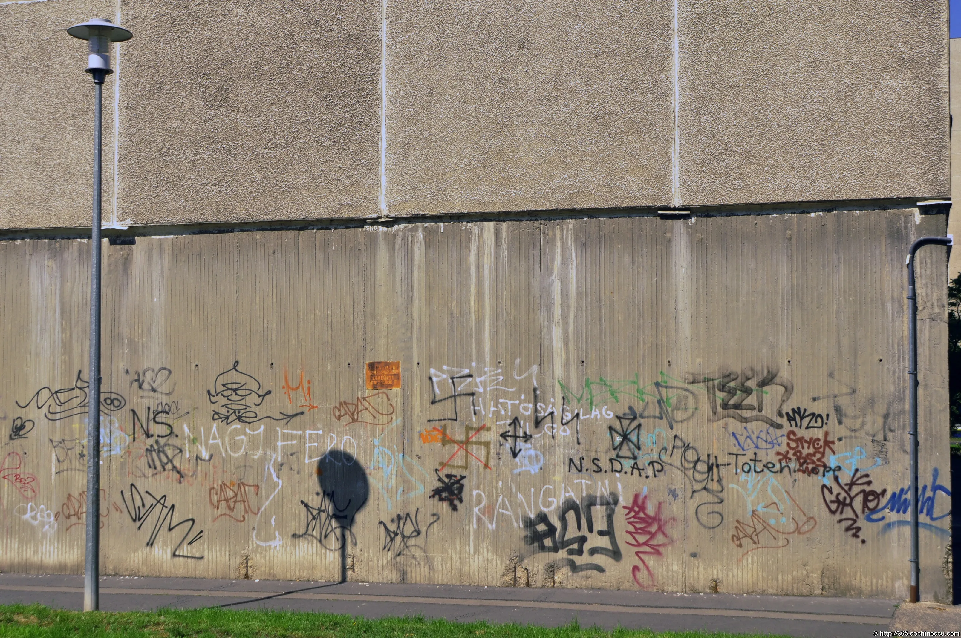 A long concrete wall is covered in colorful graffiti.
