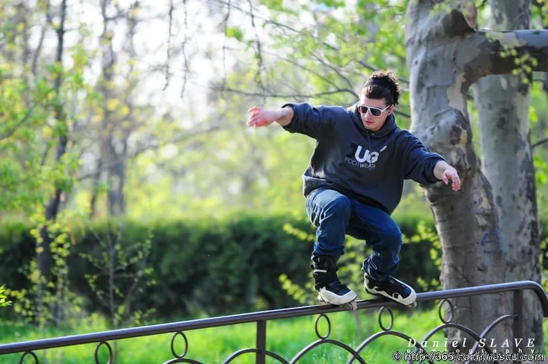 A young rollerblader grinds along a railing in a park.