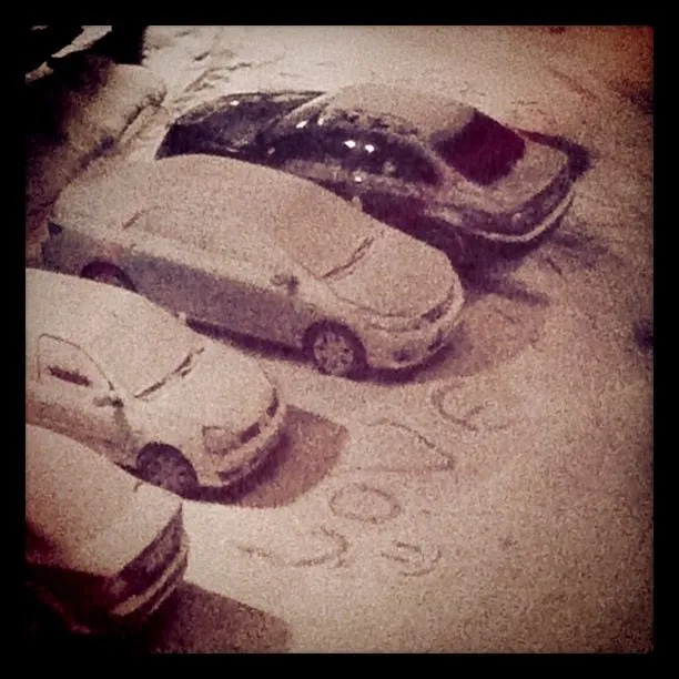 Cars parked in a snowy lot with the word Love written in the snow.