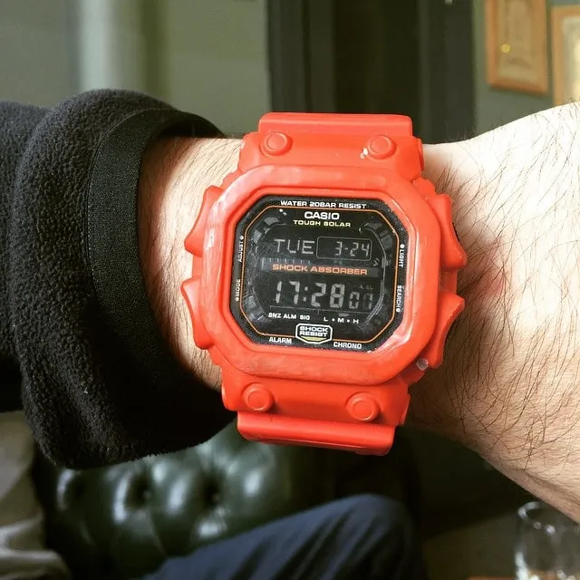 Prim-plan cu un ceas digital Casio G-Shock roșu-aprins, purtat la încheietură și afișând ora 17:28