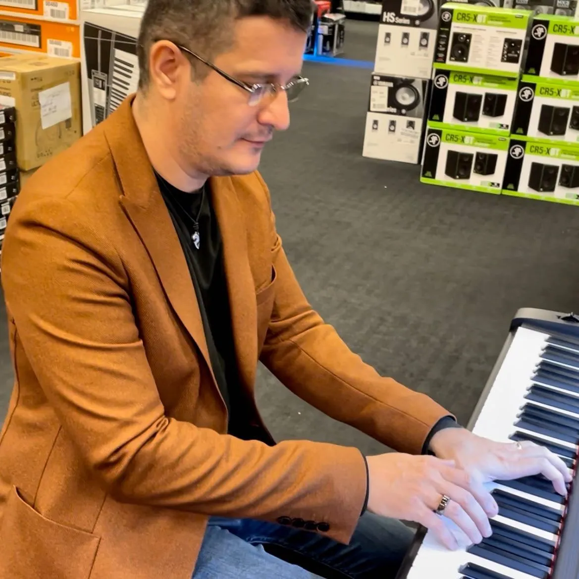 Sebastian Cochinescu plays an electronic keyboard while seated in a music store.