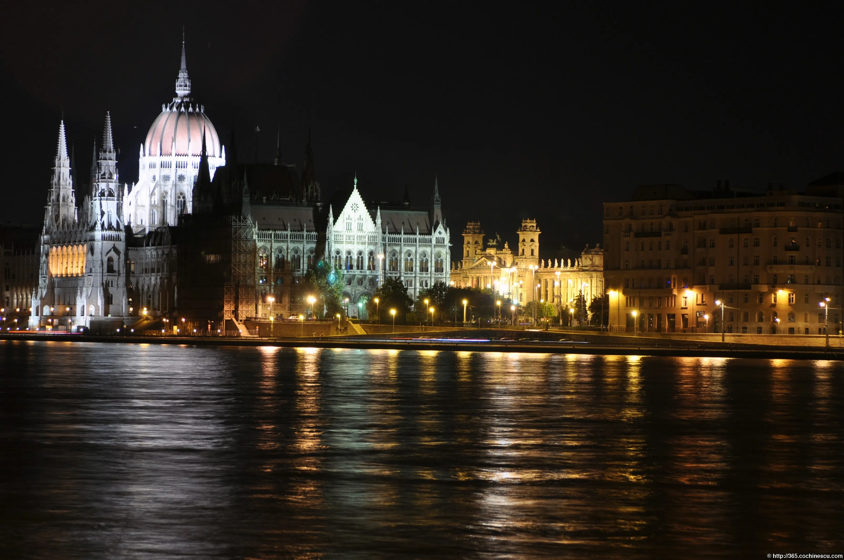 The Hungarian Parliament Building is lit up at night and reflected in the Danube.