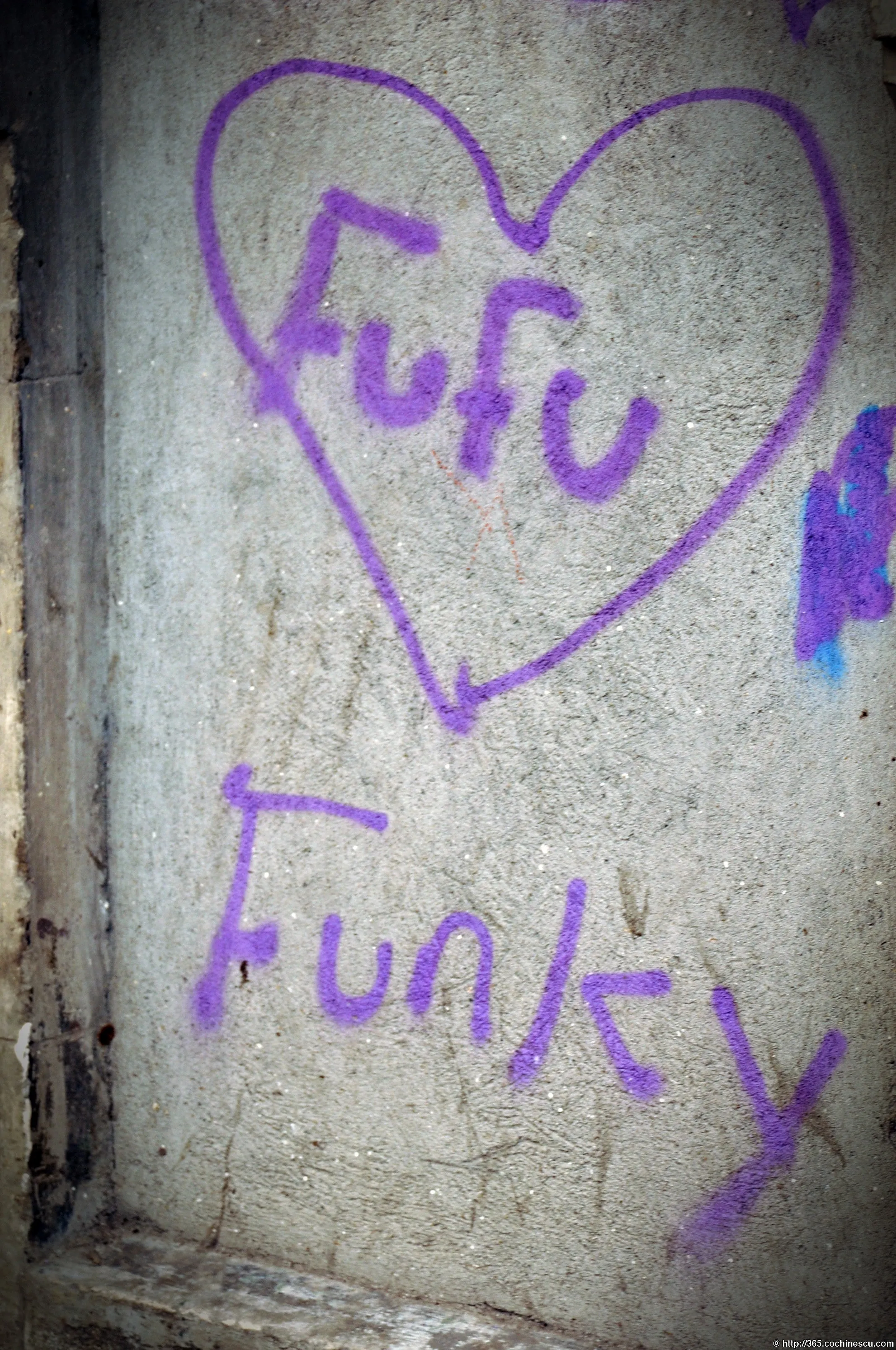 A purple piece of graffiti bearing the name Fufu is drawn inside a heart on a wall.