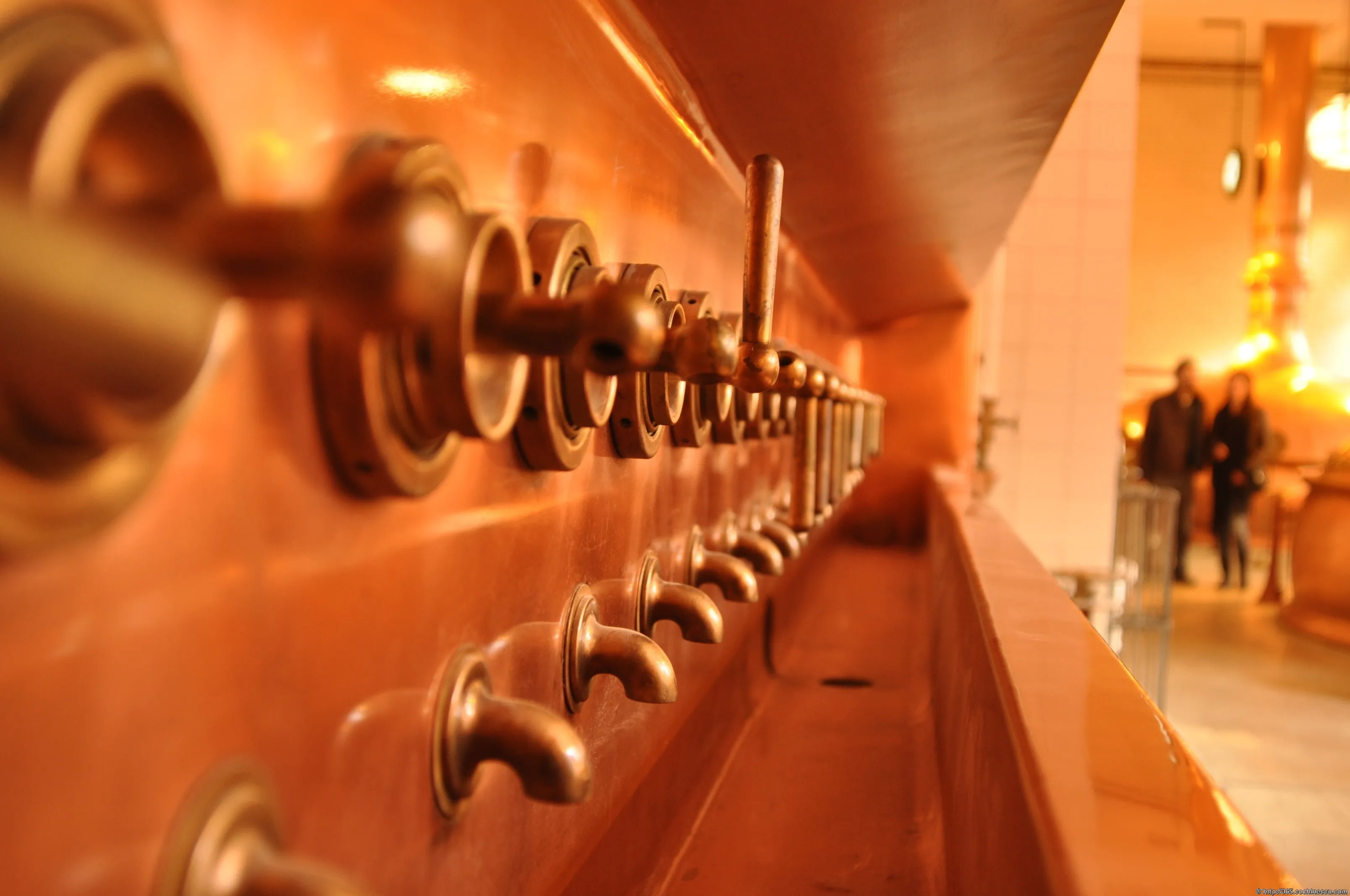 A row of metal taps is bathed in the museum’s orange light.