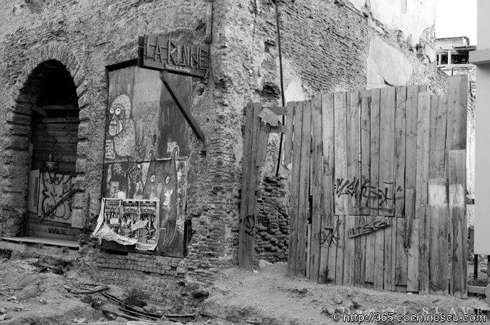 An old, run-down building is fenced off with graffiti-covered boards.