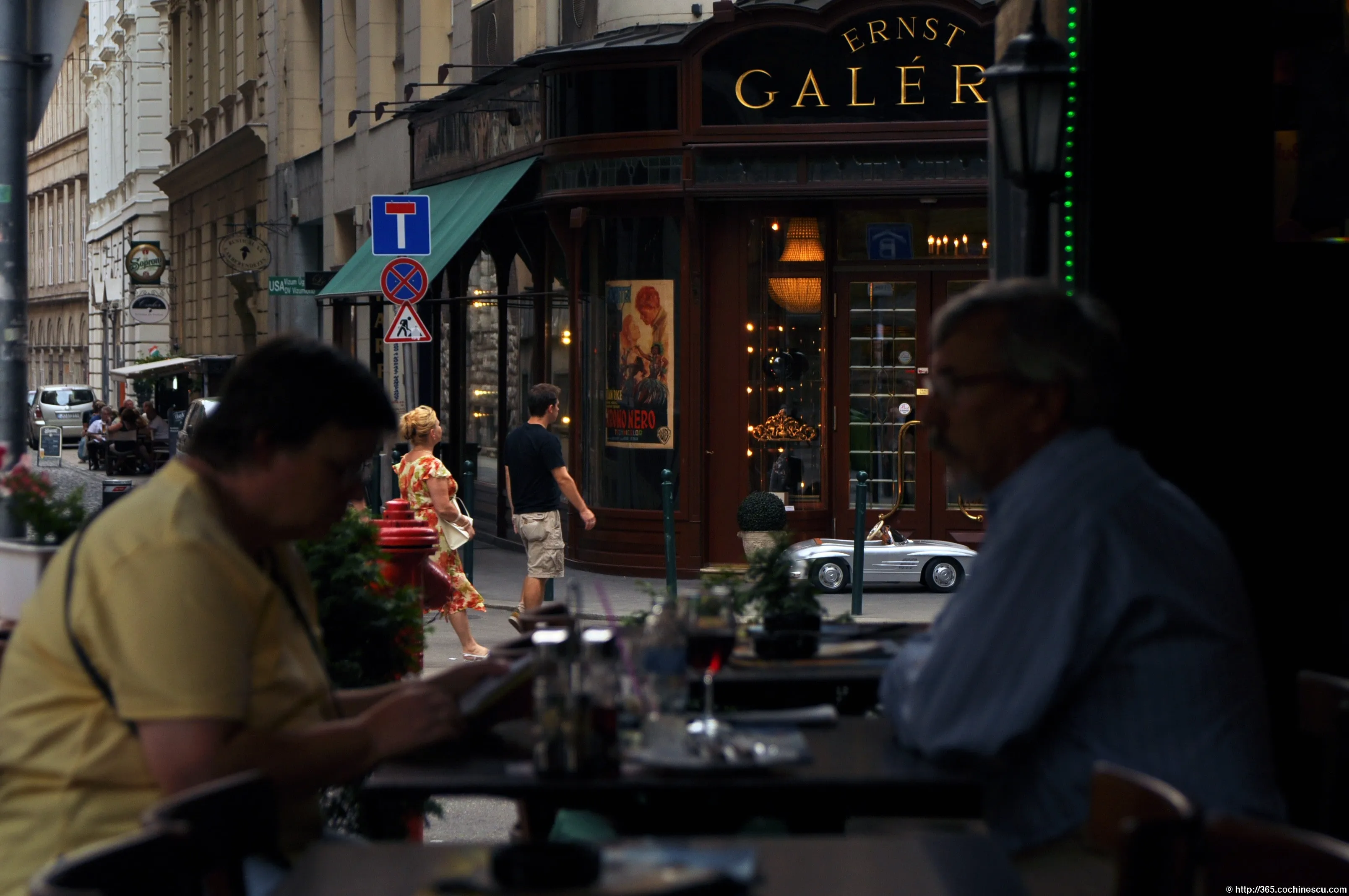 Two people sitting at a cafe table overlooking a street in Budapest.