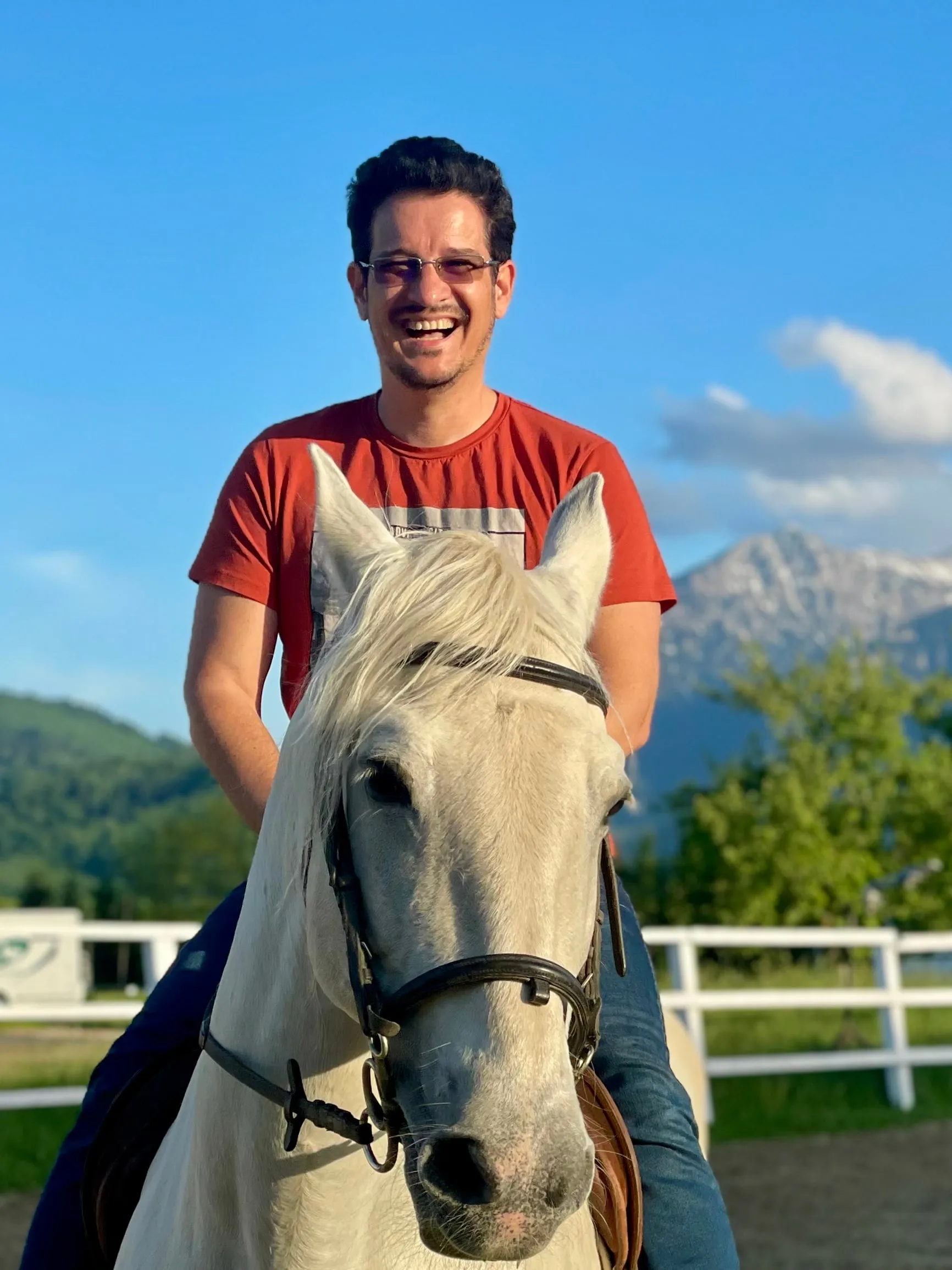 Sebastian Cochinescu smiling on a white horse, with mountains behind