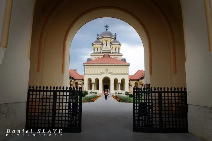 The Reunification Cathedral in Alba Iulia is framed by the gate’s arch and the open grilles.