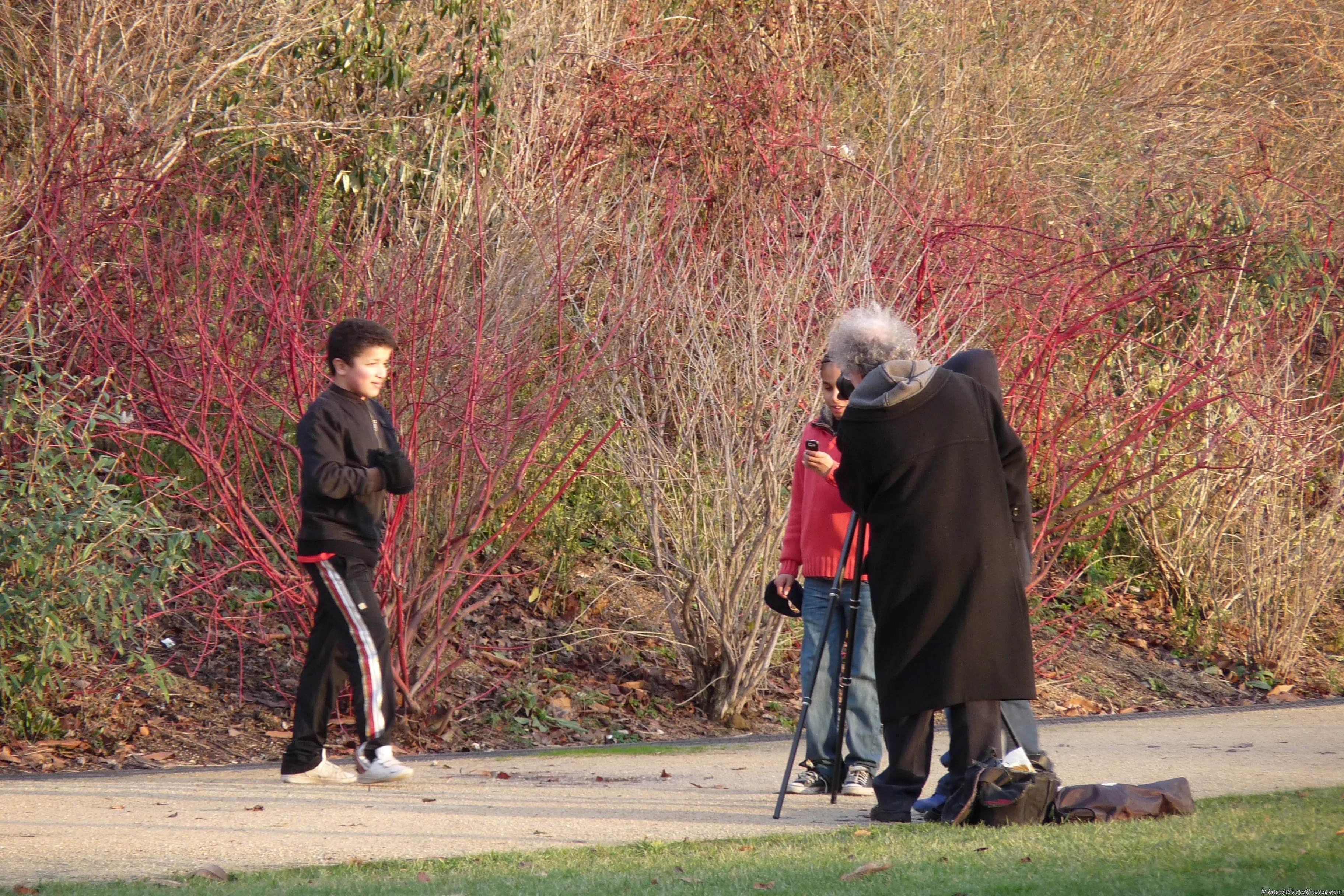 The photographer and the teenagers are looking at the images on the camera next to the tripod.
