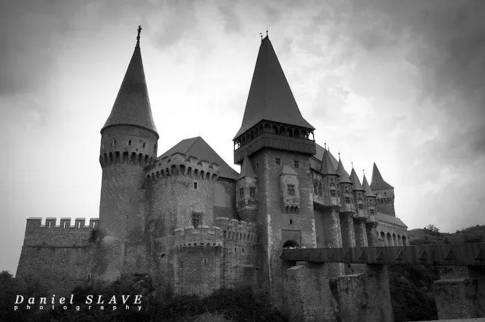 Corvin Castle and its access bridge are captured in a black and white photograph.