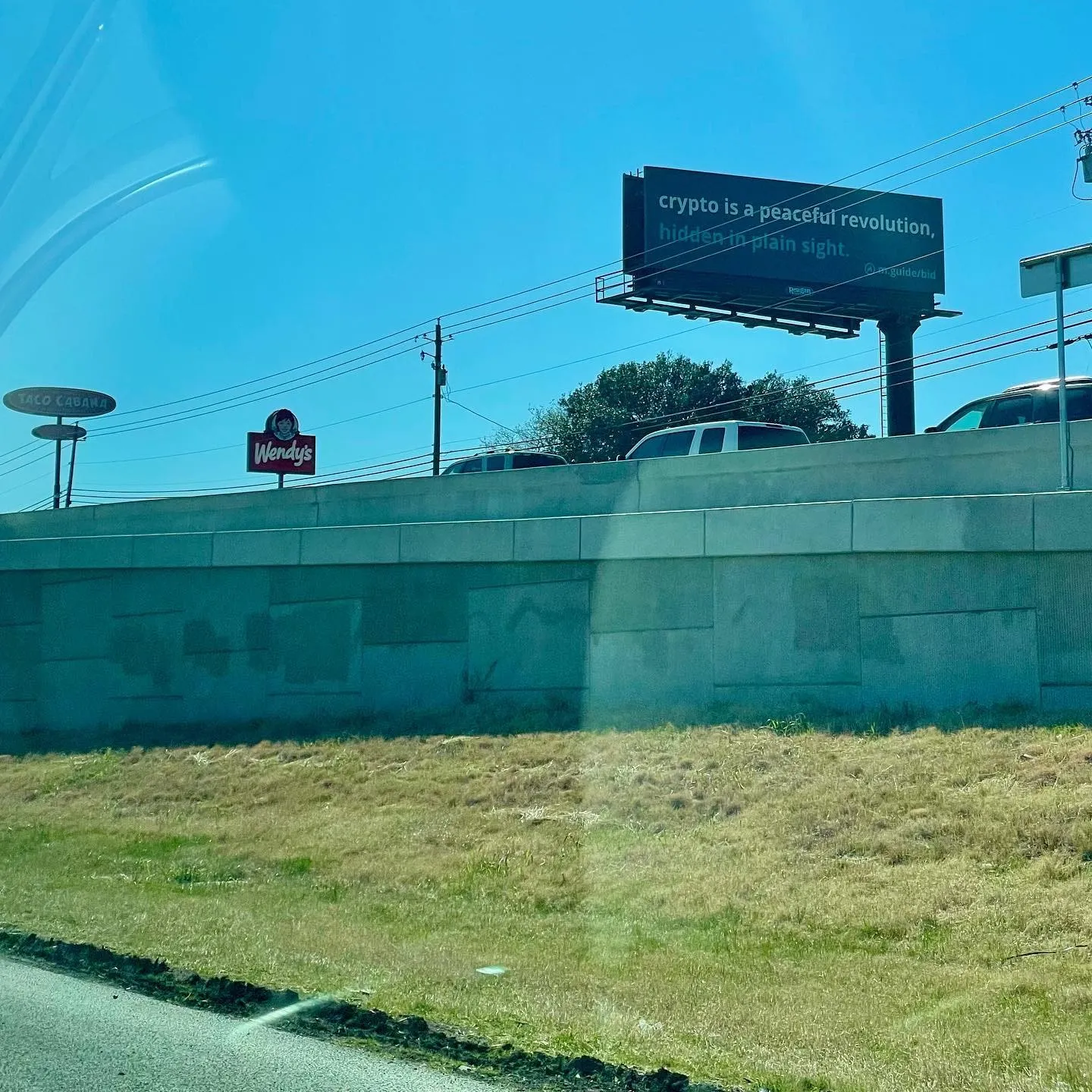 A roadside billboard declares that crypto is a peaceful revolution hidden in plain sight.