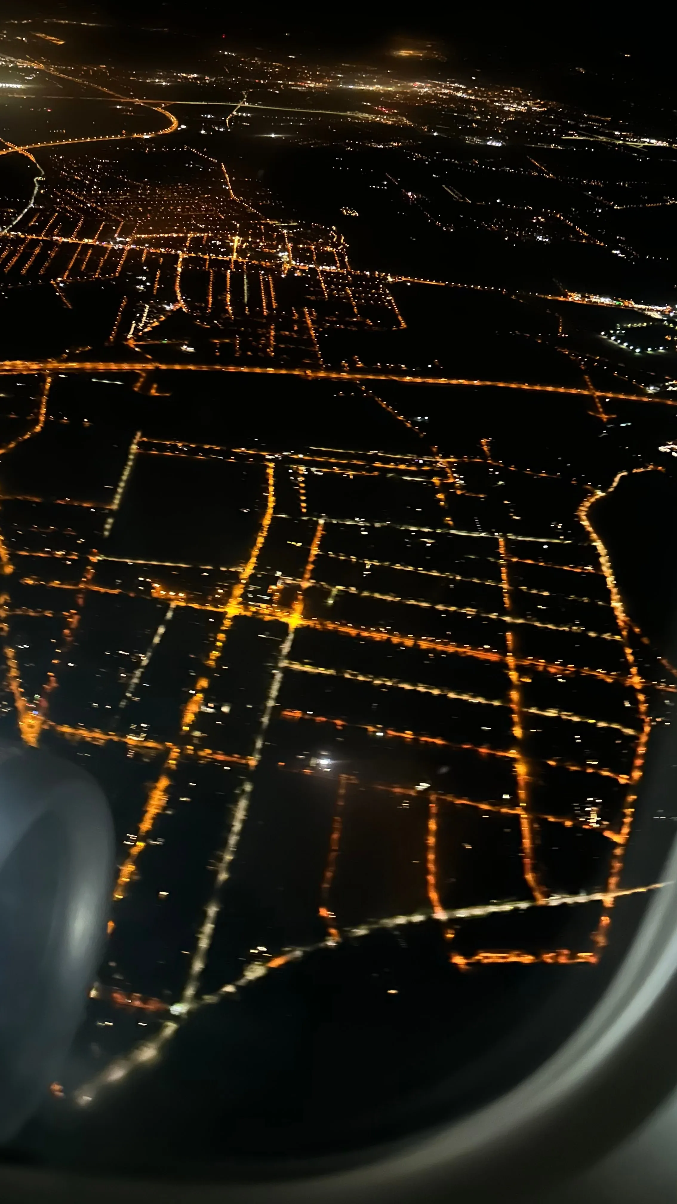 City street grid glowing at night, seen from a plane window