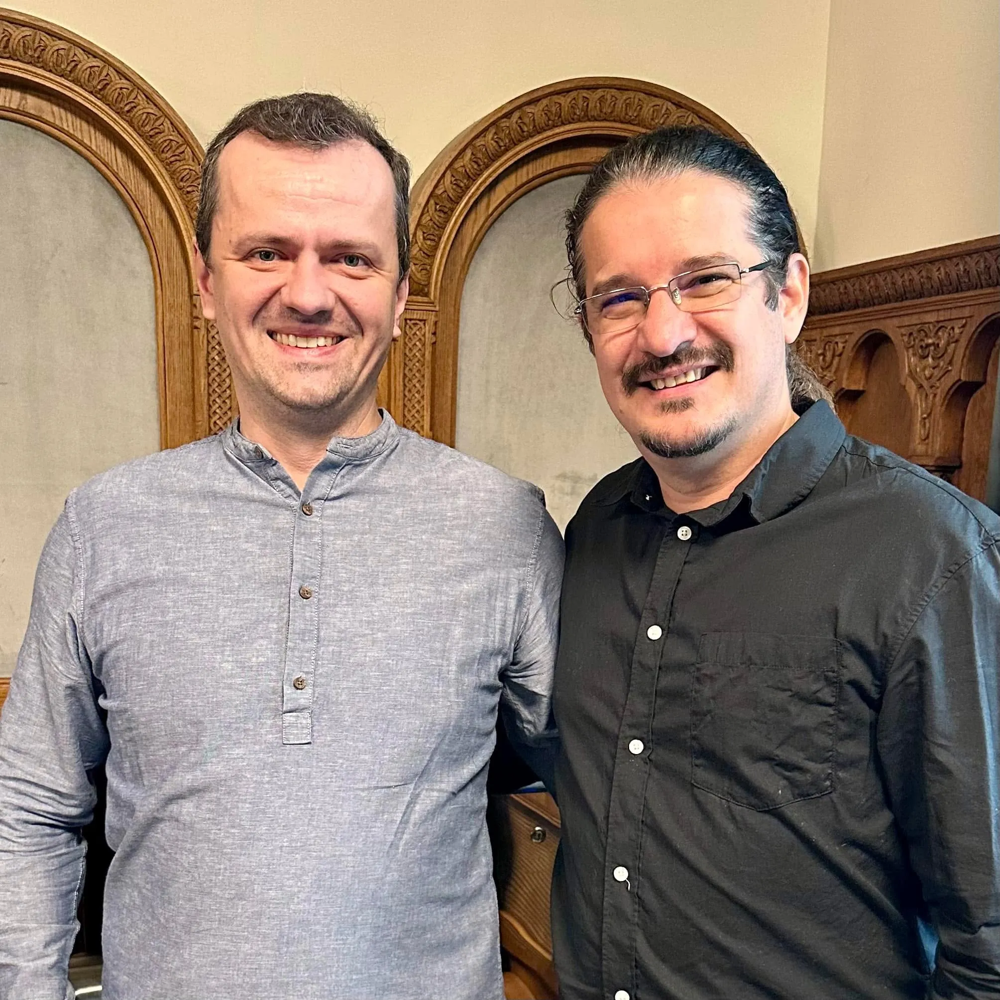 Marius Istrate and Sebastian Cochinescu stand together smiling in an ornate wood-paneled room.