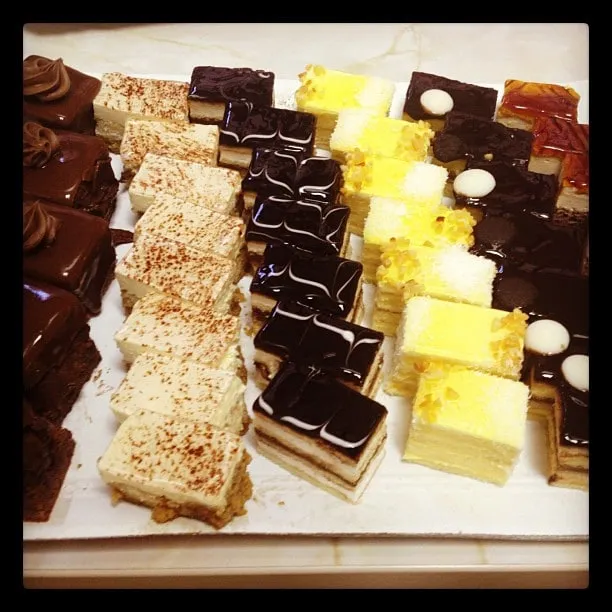 A tray of assorted cakes: chocolate, cream-filled, dark-glazed, and yellow cakes.