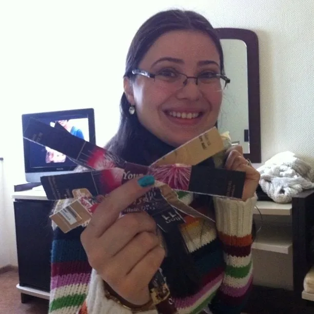 Young woman with glasses smiles while holding a makeshift sorcova made from cigarette packs