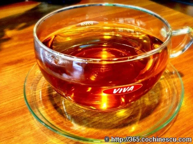 A clear cup of mint tea sits on a wooden table.