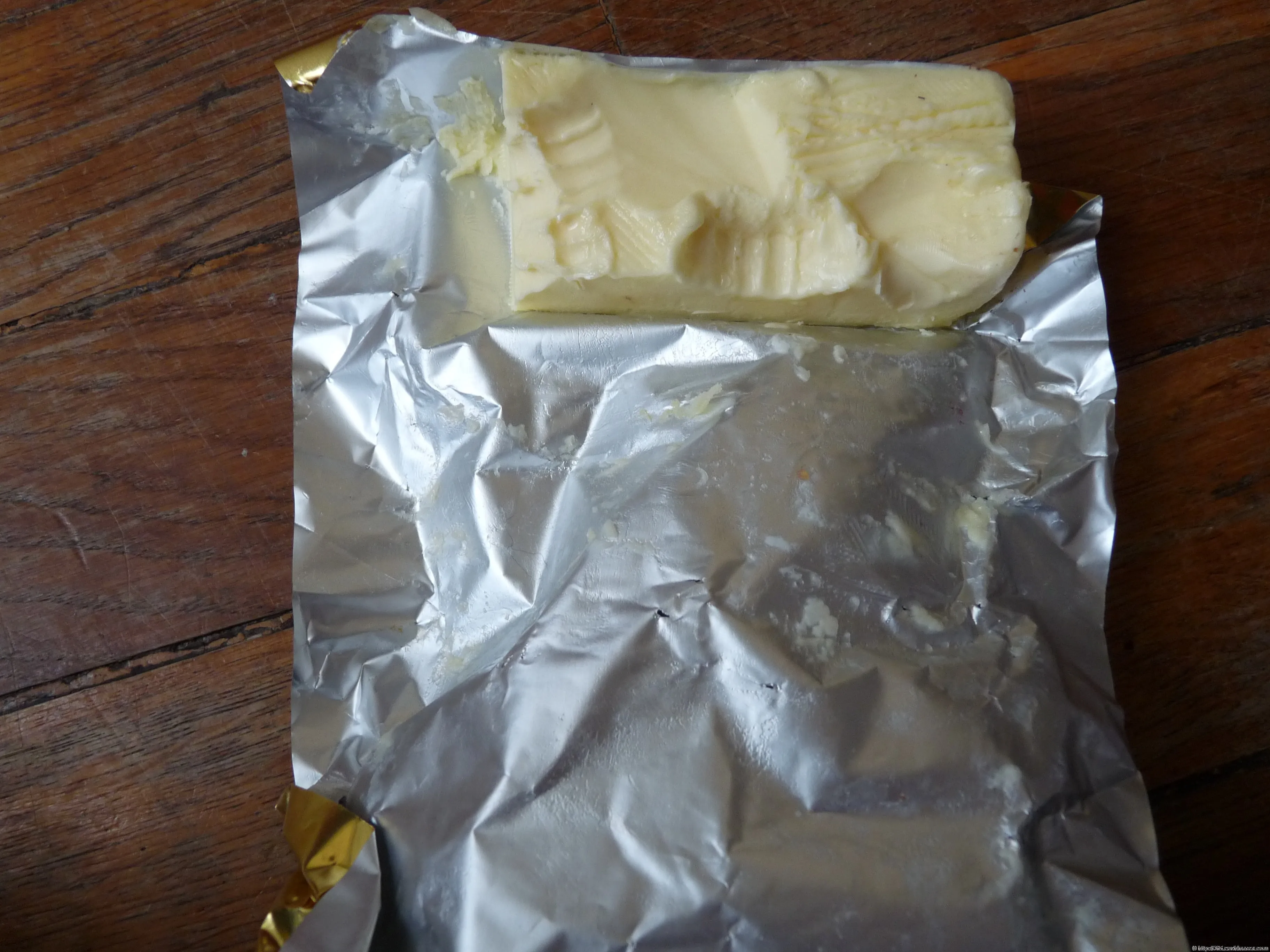 An open packet of butter on a wooden table.